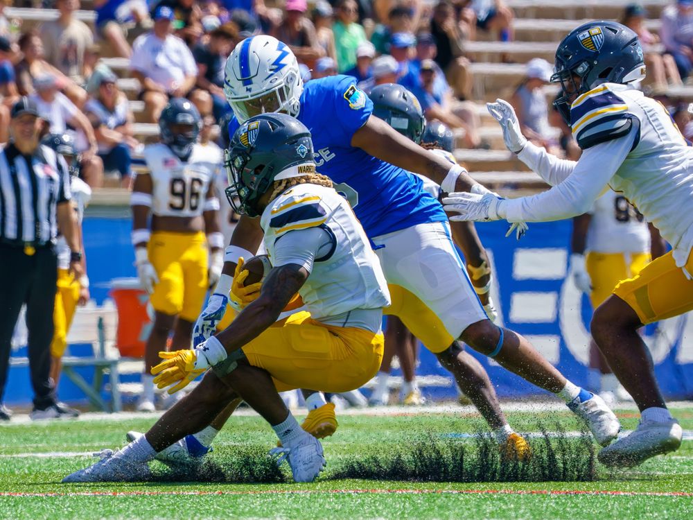 Football players collide in aggressive tackle during intense game action.