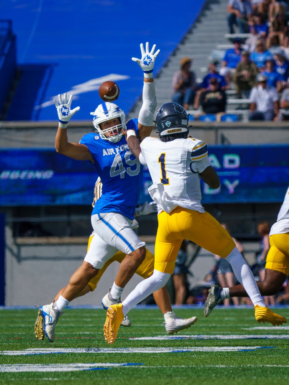 Football players leap and battle for the ball during competitive game play.