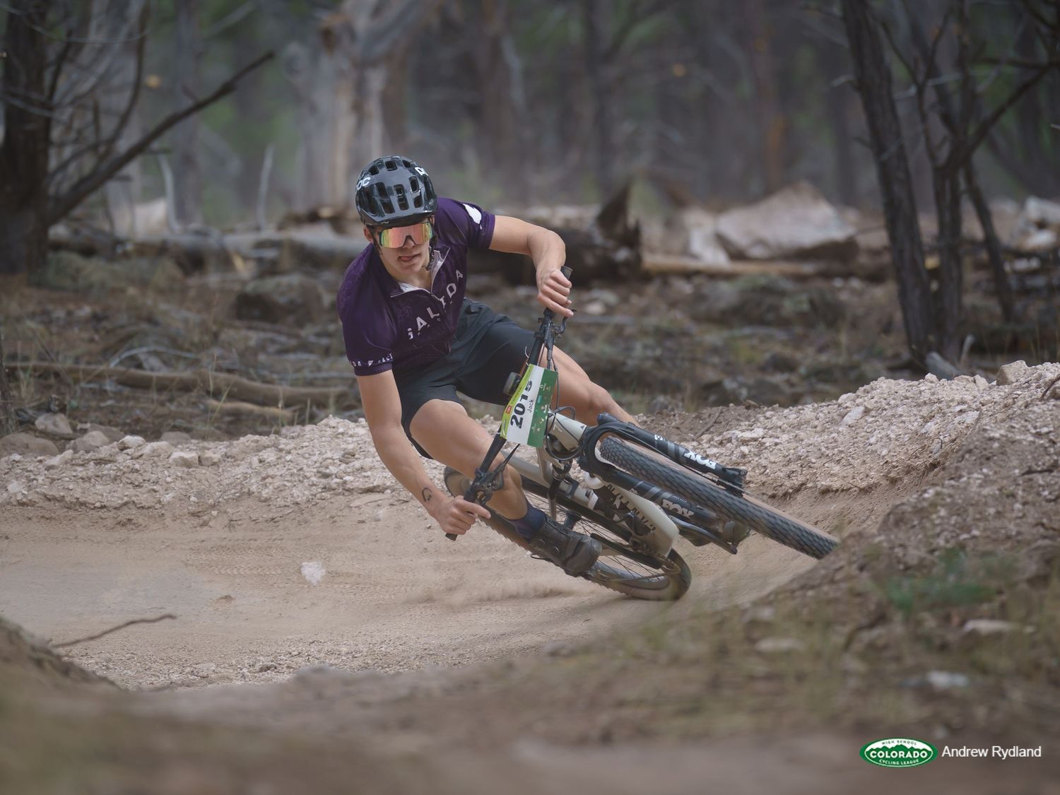 Mountain biker leans into a sharp dirt trail turn during an intense ride.