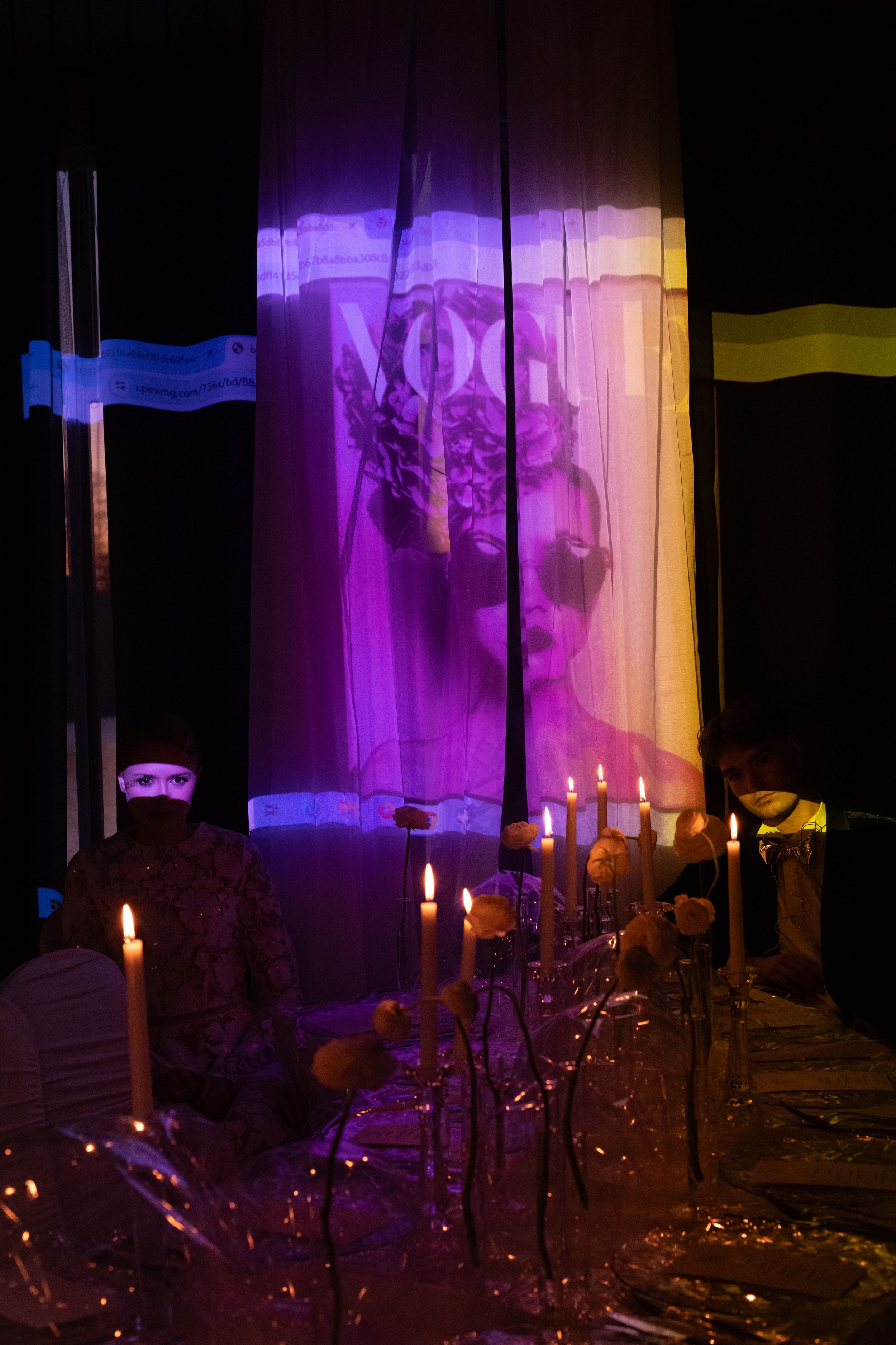 Spooky Halloween scene with lit candles and ghostly purple lighting casting shadows on decorative display.