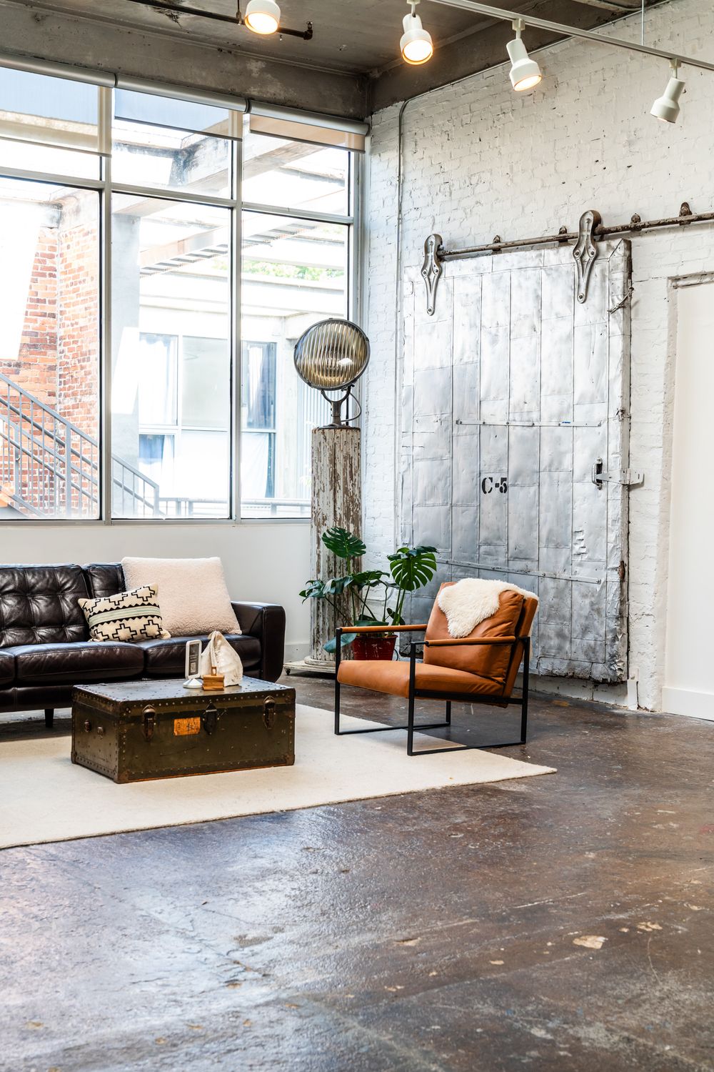 Modern industrial living space with leather furniture, sliding barn door, and large windows.