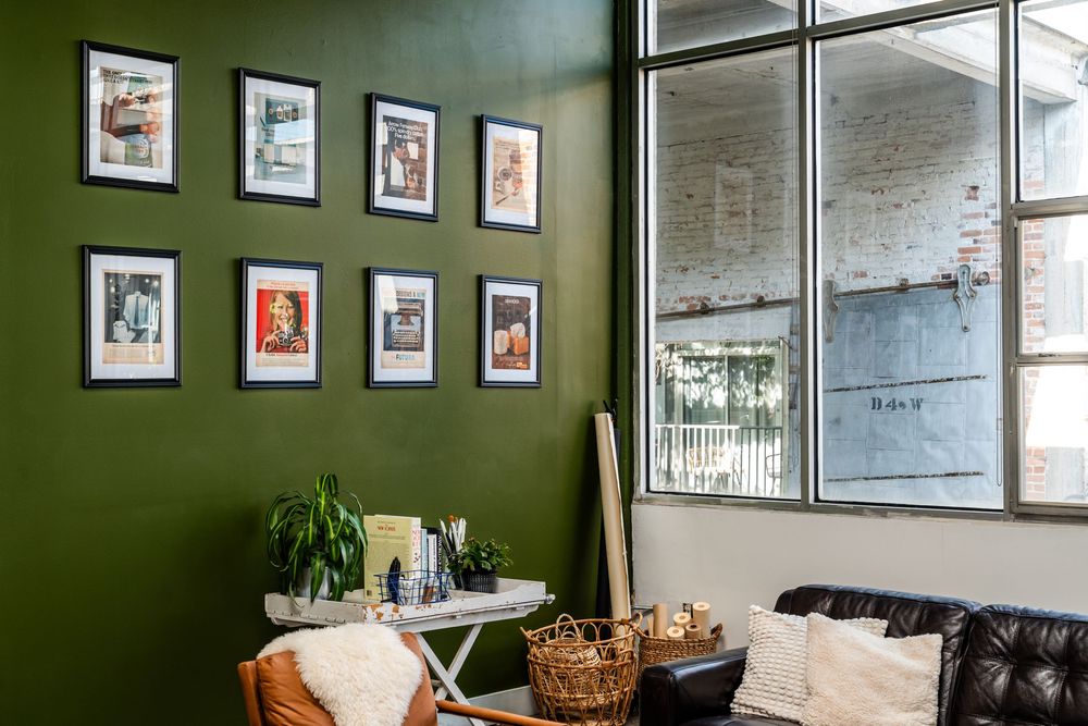 Green accent wall with framed artwork in a modern industrial style room.