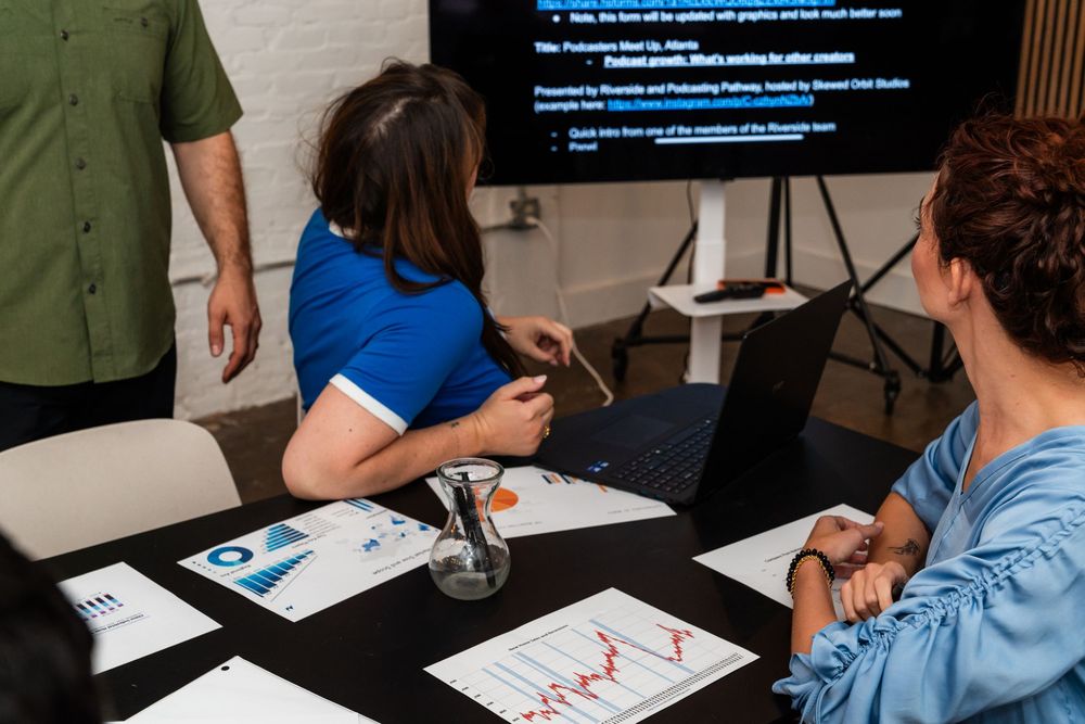 Business team analyzing data and charts during a meeting with laptop and TV display.