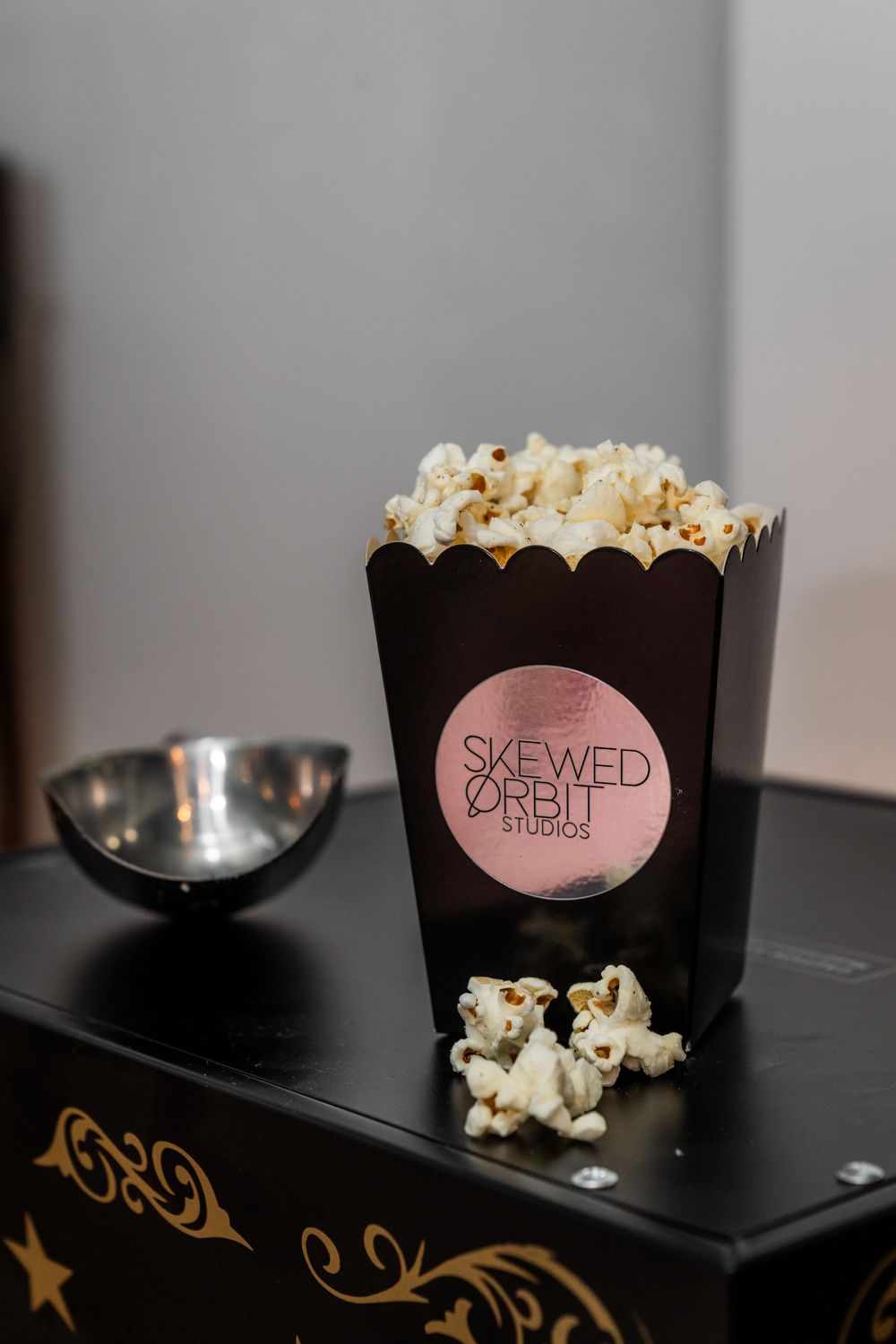 Box of popcorn labeled 'Skewed Shell' with scattered kernels on black surface.