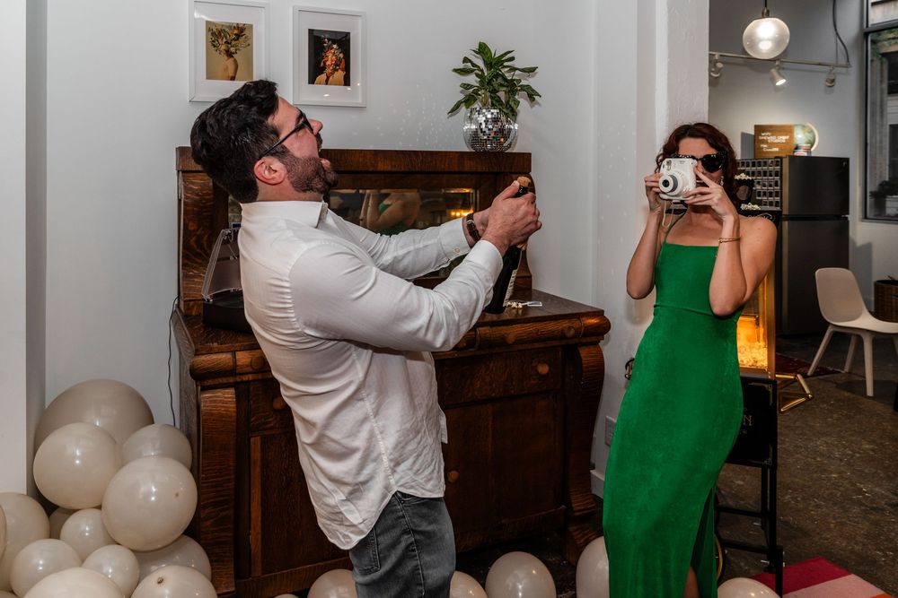 Couple taking photos in room with vintage furniture and balloon decorations.