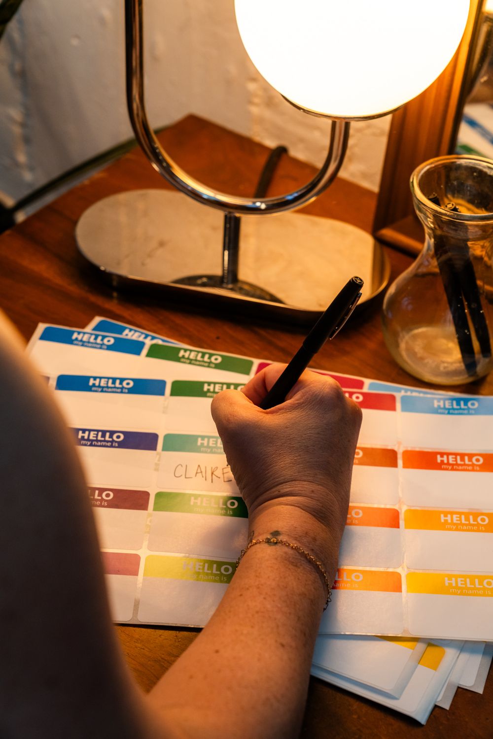 Colorful name tags and writing materials illuminated by table lamp.