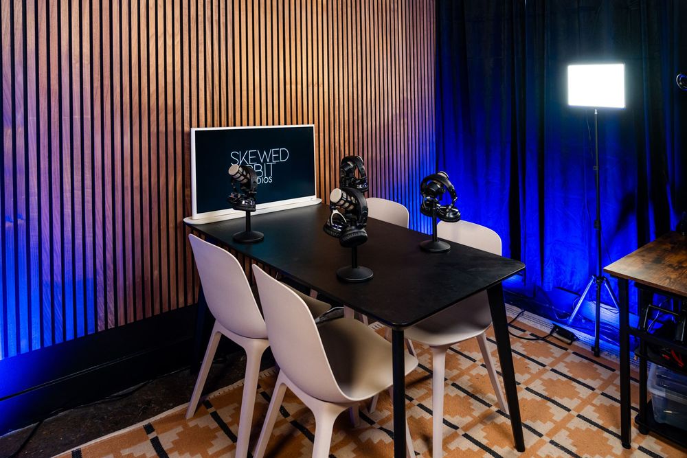 Modern podcast studio interior with wooden chairs and blue accent lighting.