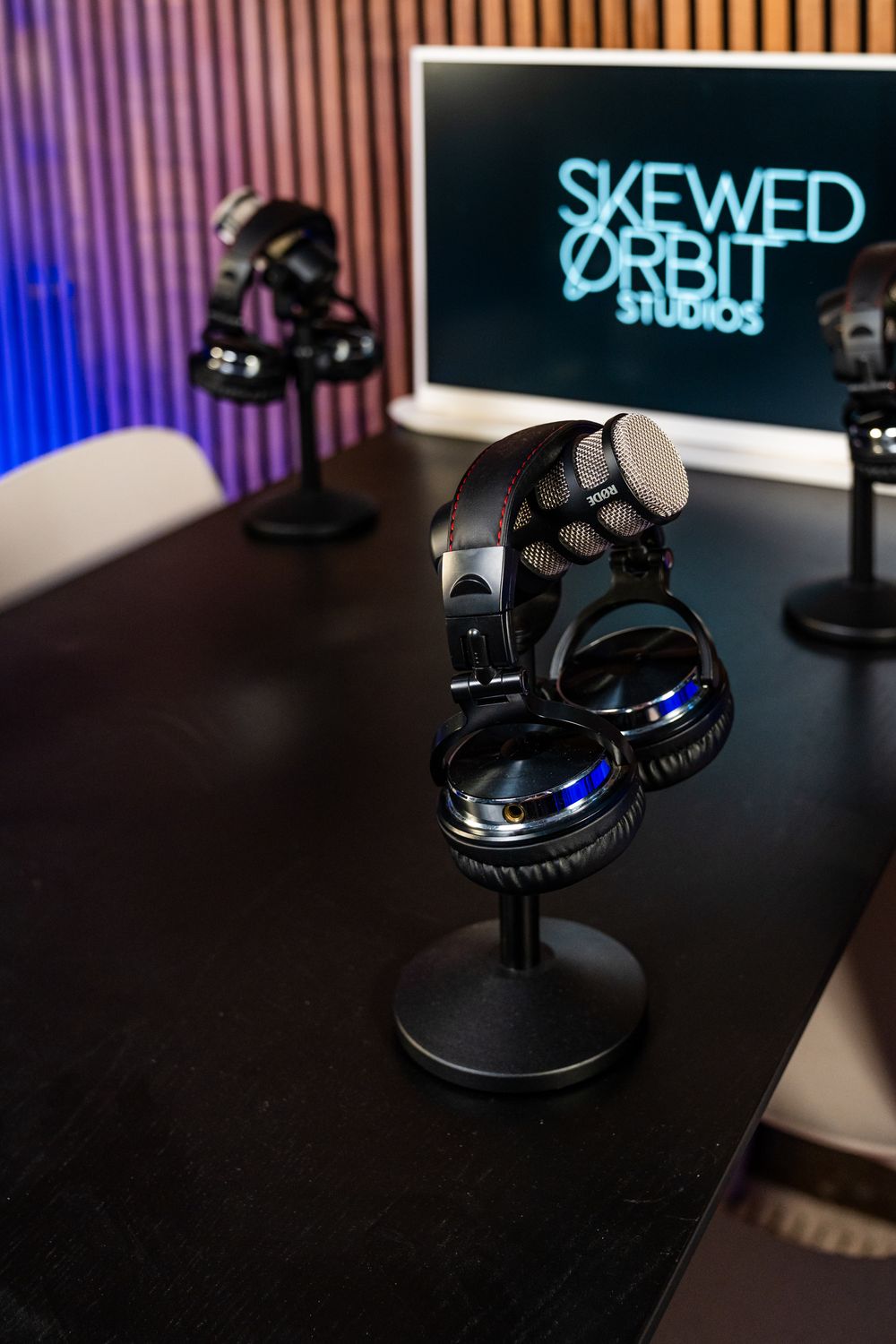 Close-up of professional headphones on black surface with blue lighting and studio logo.