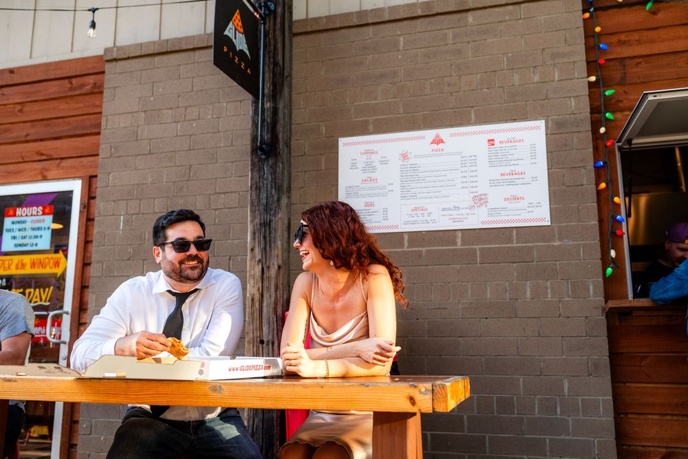 Casual outdoor dining scene at a restaurant patio with customers enjoying a meal at a wooden table.