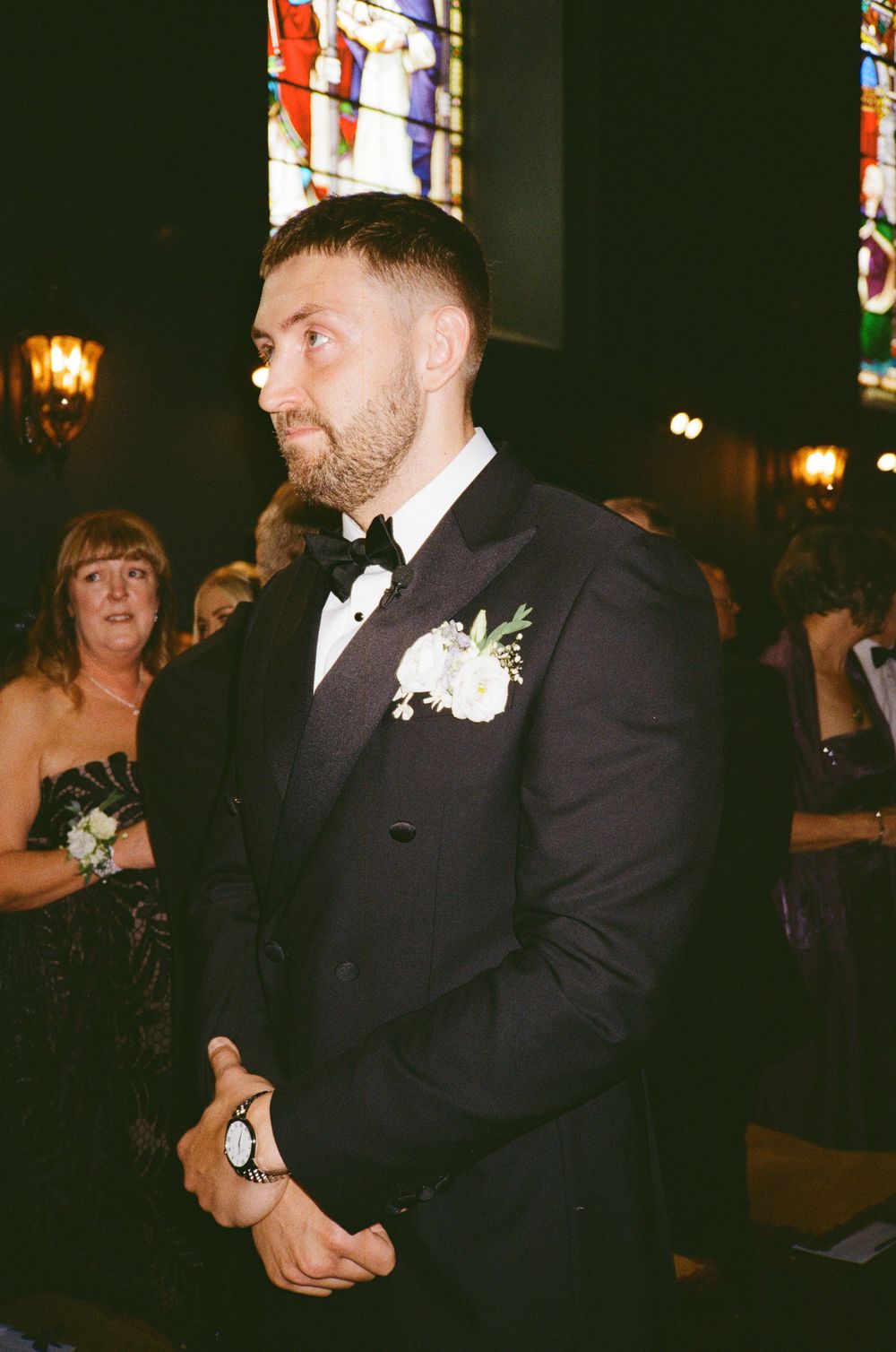 Guests dance together at an elegant wedding reception with warm lighting and dark decor.