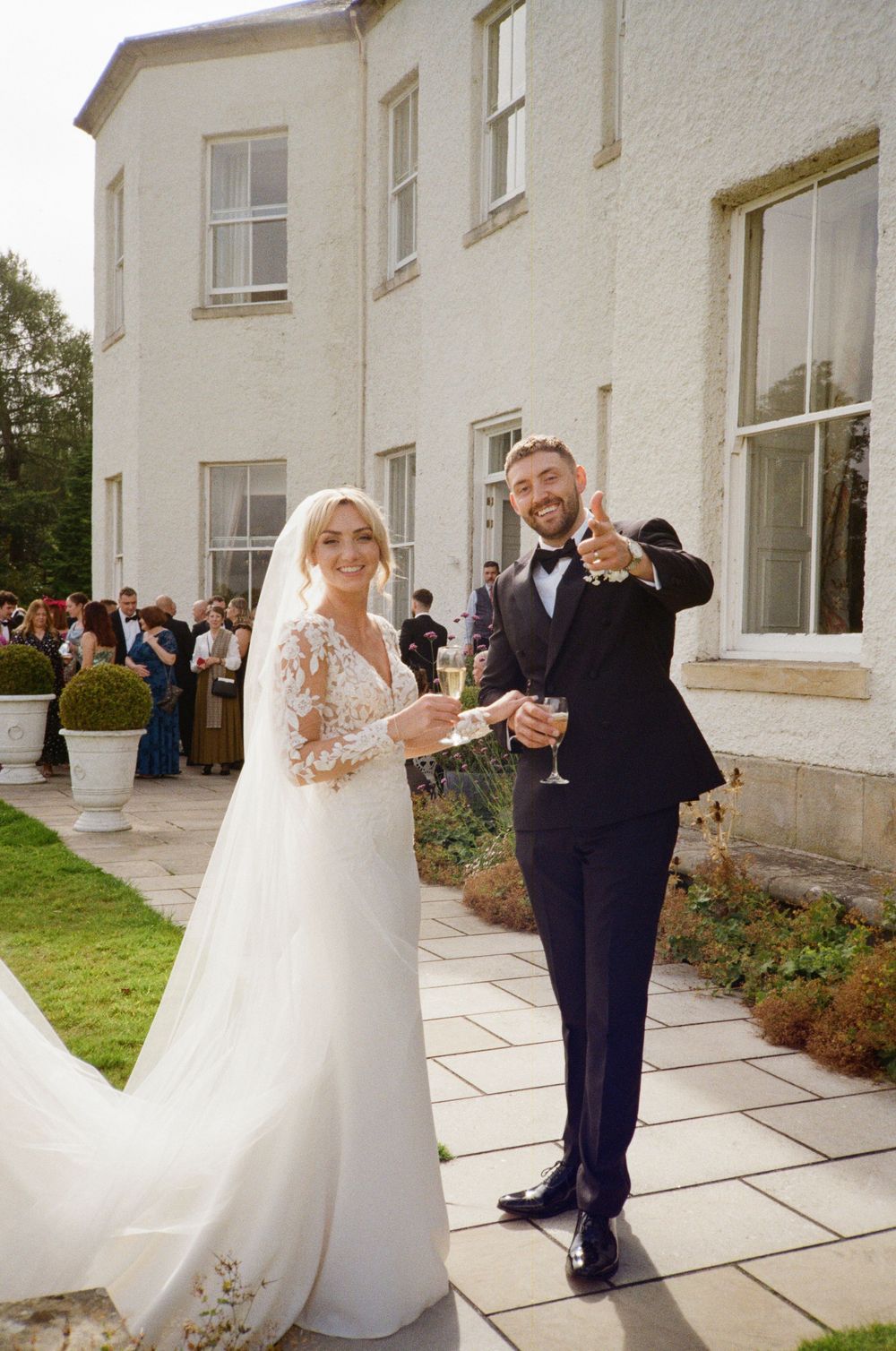 A couple shares a romantic dance moment outside a white manor house with elegant columns and windows.