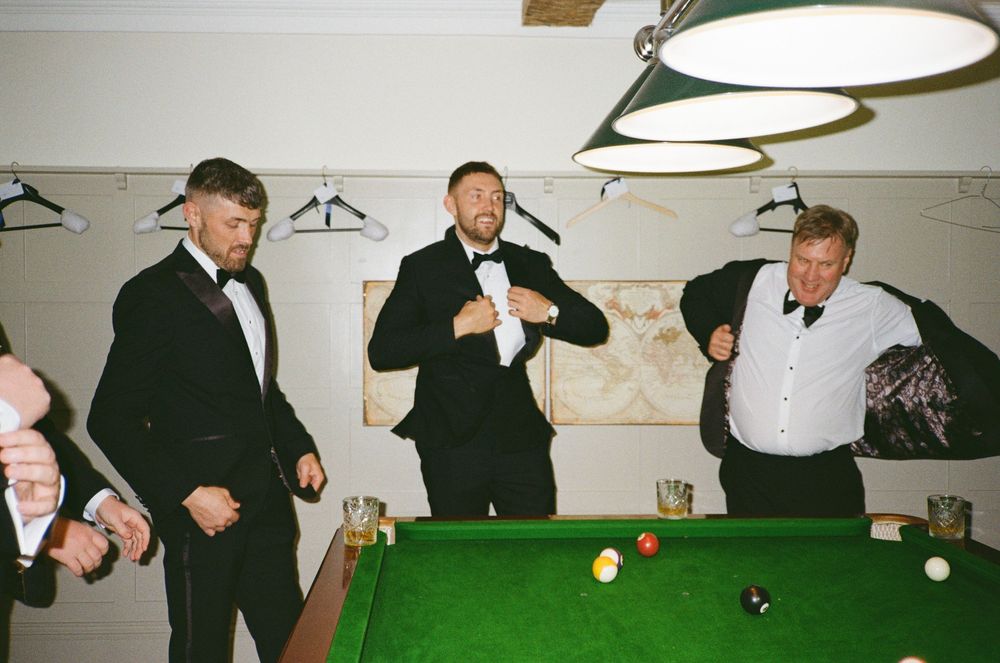 A sequence of pool players taking shots at a green billiards table under overhead lighting in a game room.