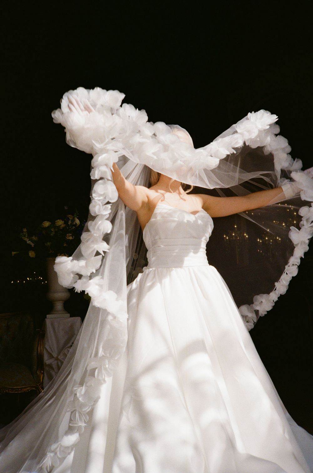 A flowing white wedding dress twirls gracefully in a dance-like motion against a dark background.