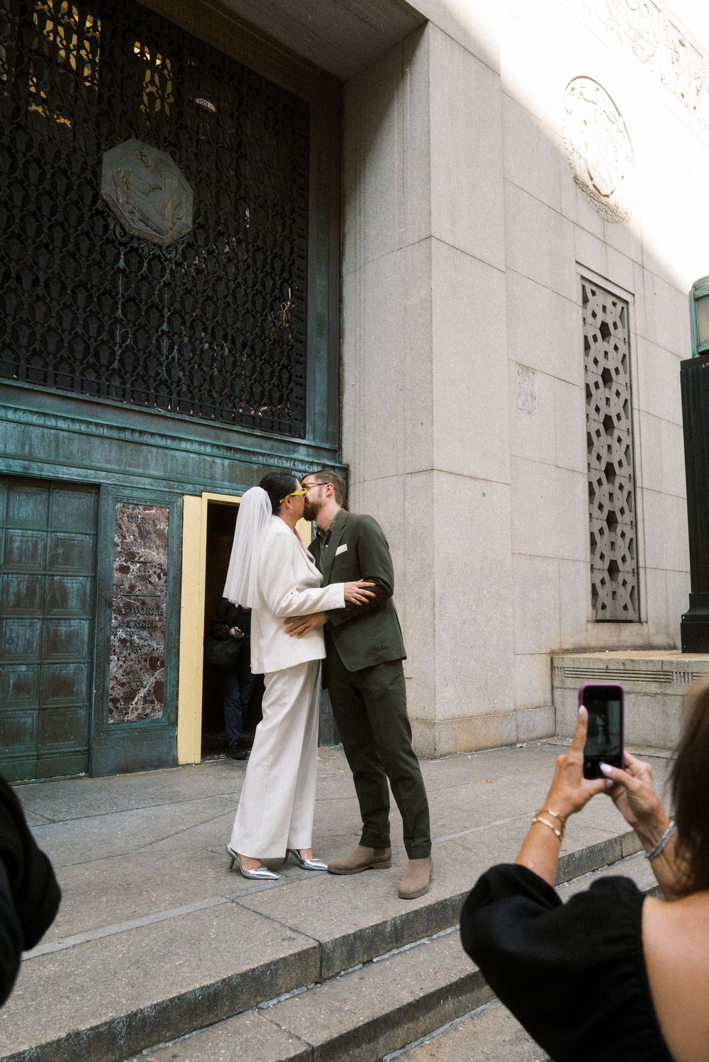 A sequence of images showing two people in formal attire standing and embracing near a stone building entrance.