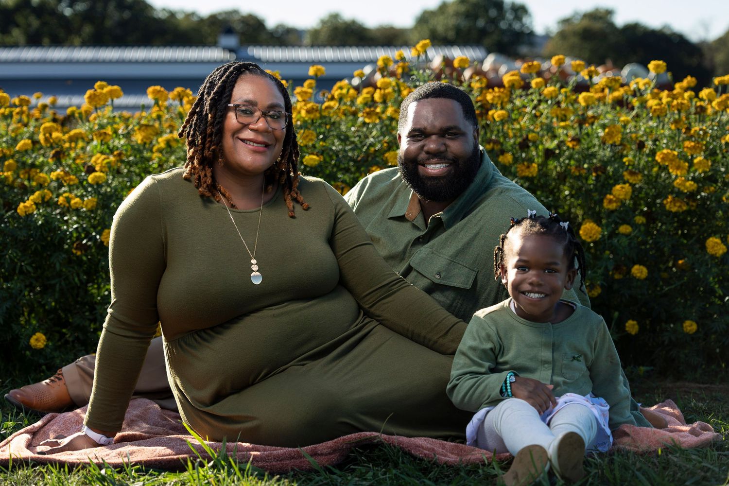 Family relaxing on blanket in field of bright yellow sunflowers on sunny afternoon at Rivercrest Orchard in Fayetteville AR. Taken by Trevel