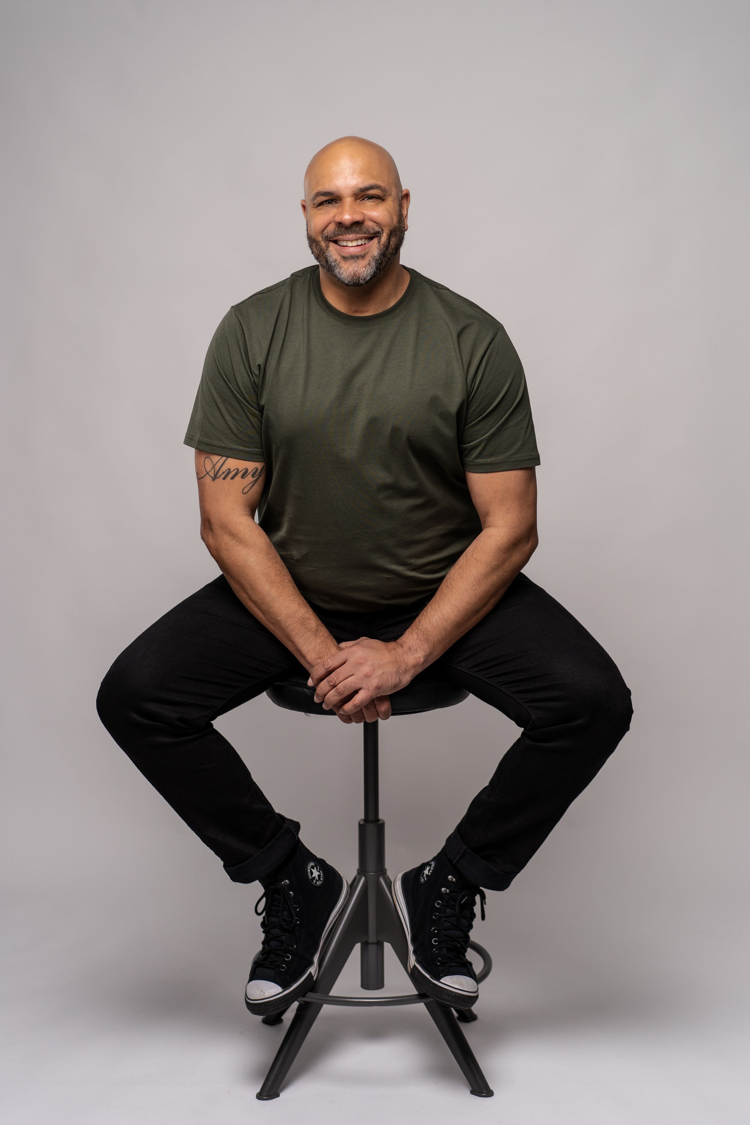 Hampshire based photographer Steve Currie sits on a stool in a photo studio in Winchester.