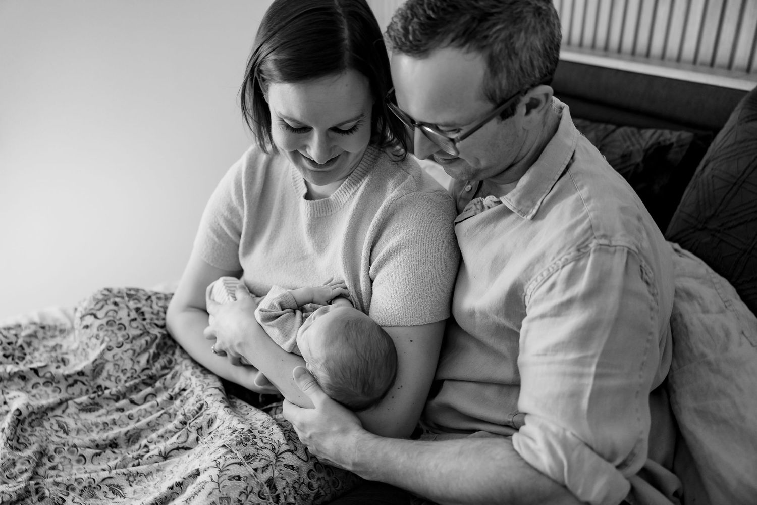 Black and white photo series showing tender family moments with a young baby and parents at home.