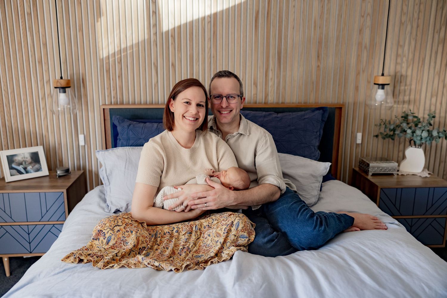 Intimate bedroom photo with wooden wall paneling and blue headboard details.