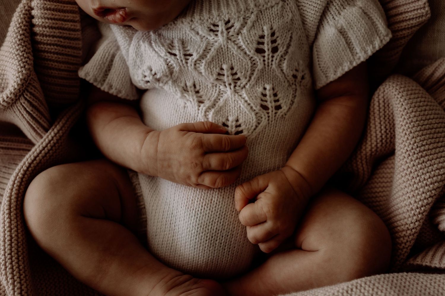 Detail shot of knitted white sweater texture with gentle natural lighting.
