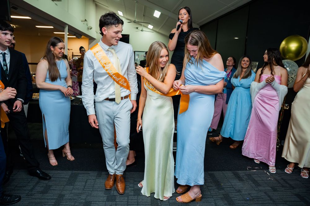People in formal attire dancing and socializing at a party with guests wearing pastel dresses and suits.