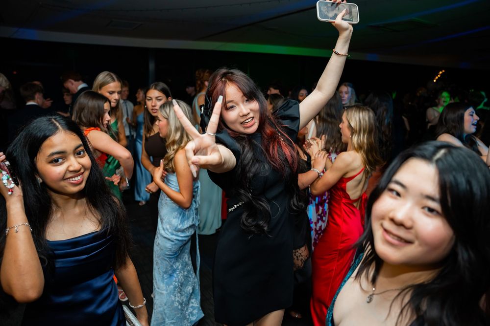 A crowded nightclub dance floor with people enjoying themselves and raising drinks in celebration.