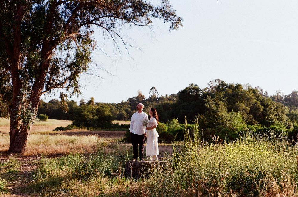 Nostalgic film photography of an intimate moment in the meadow with soft, glowing foreground textures.
