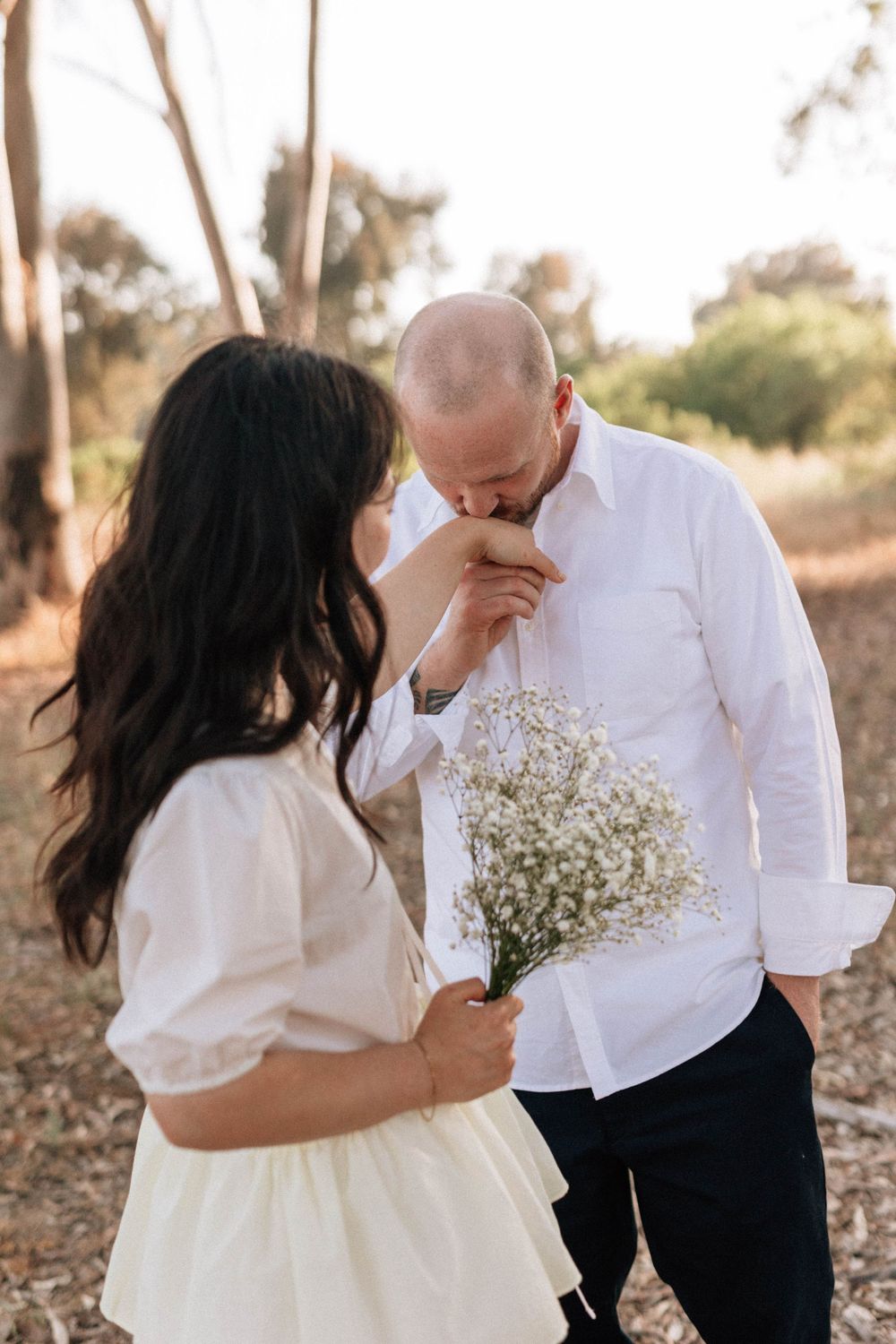 Romantic 35mm film shot of a man kissing his fiancée's hand in the scenic Ojai Valley.