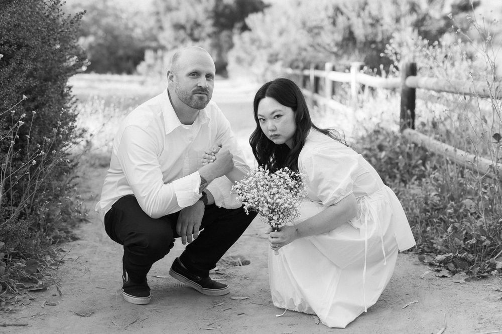 Playful yet serious black and white 35mm film shot of the bride and groom holding hands.