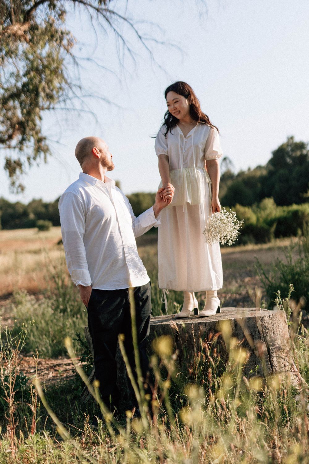 Ojai film photographer capturing a playful portrait of the bride standing on a rustic tree stump.
