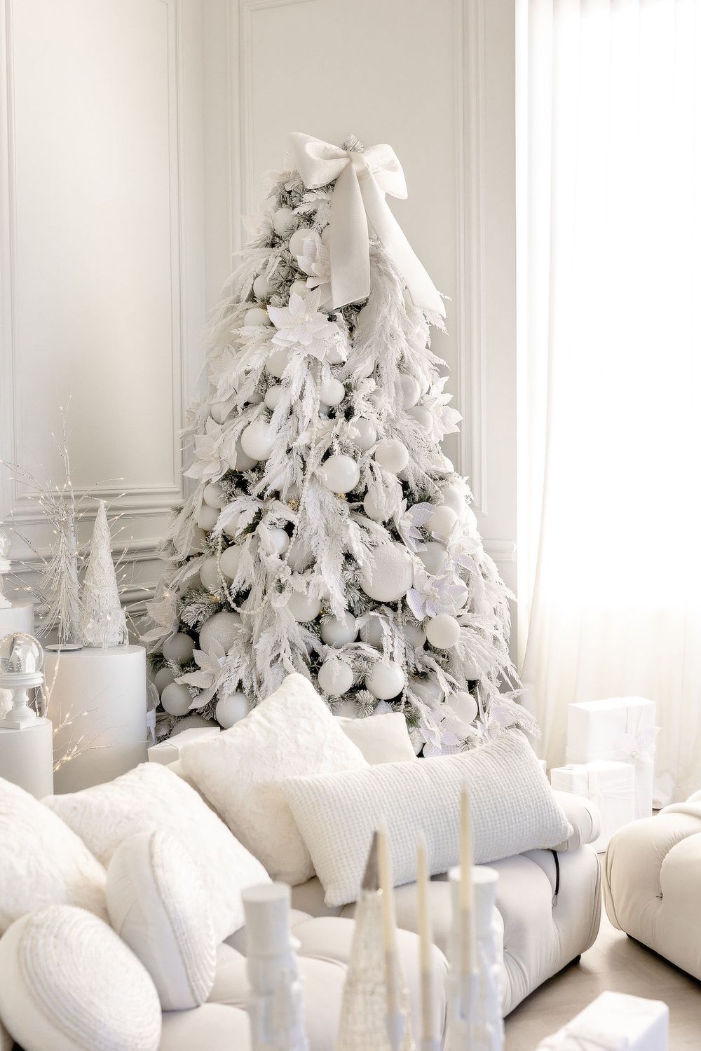 White festive Christmas trees decorated with soft lights and ornaments create an elegant winter wonderland display.