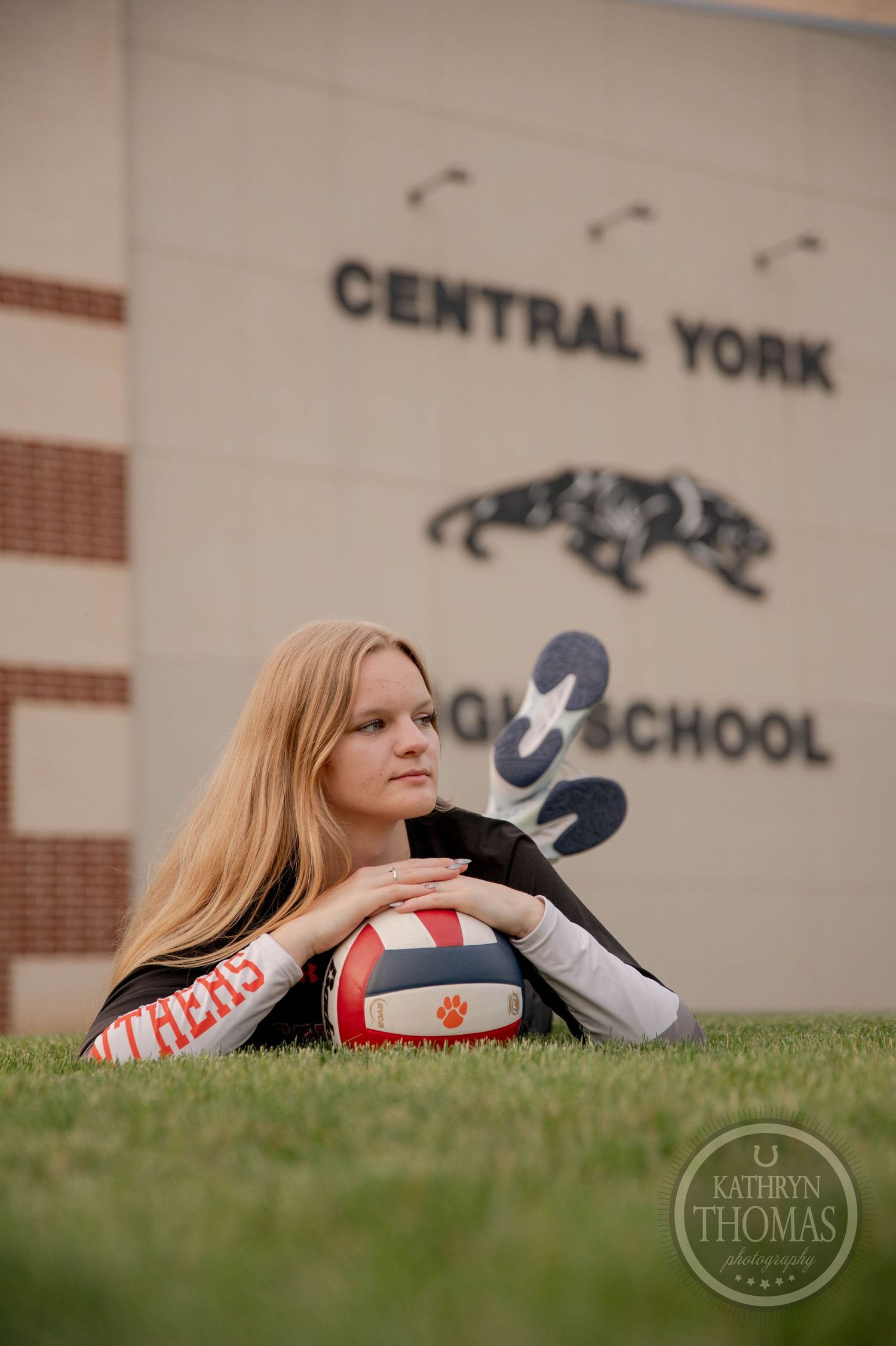 Student athlete poses with volleyball in front of Central York High School building with sports mascot logo.