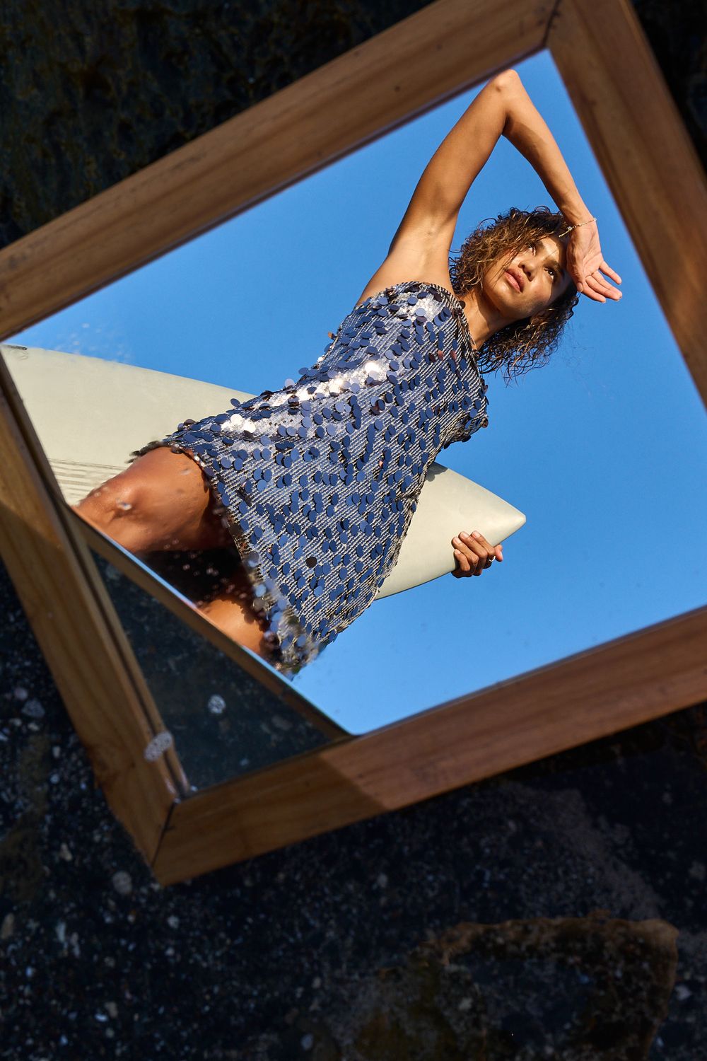 Creative series of photos showing a person reaching through a wooden window frame against a bright blue sky background.