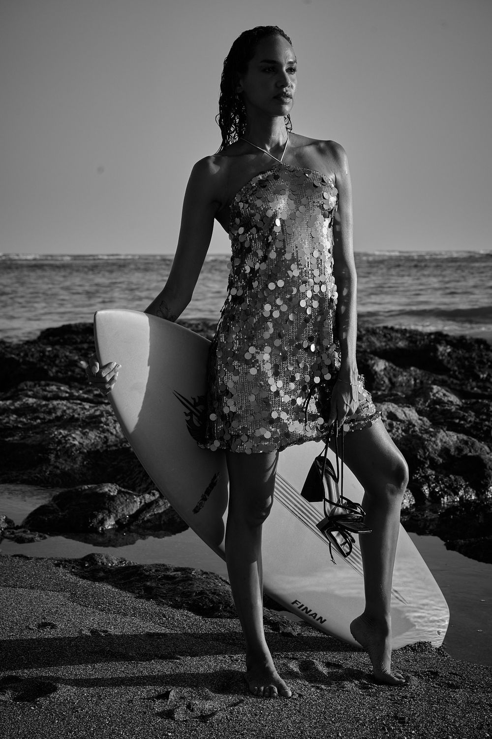 Black and white photo series of a person walking along a rocky beach shoreline.