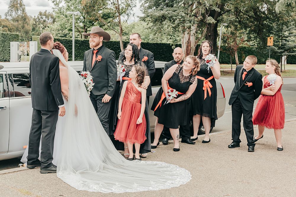 Wedding guests enjoy outdoor ceremony seating while elegantly dressed people gather and socialize at garden venue.