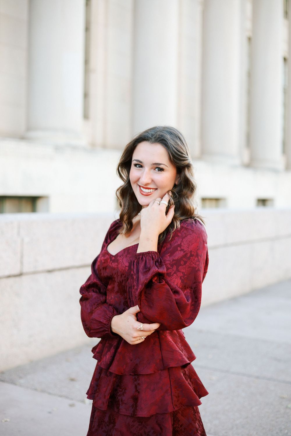 Fashion portraits showing burgundy ruffled dress against white columns.