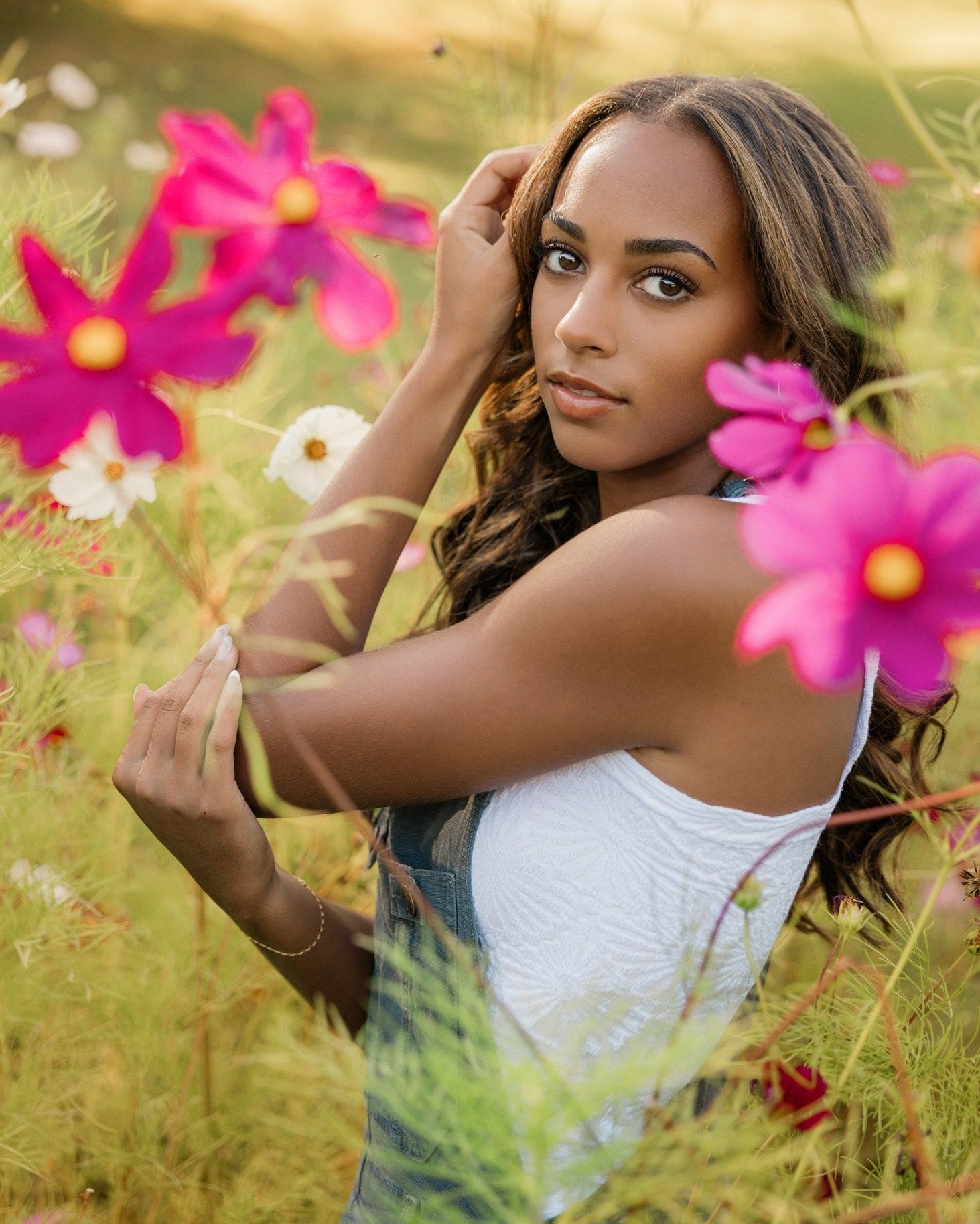 Outdoor portrait session in a field of vibrant pink cosmos flowers during golden hour.