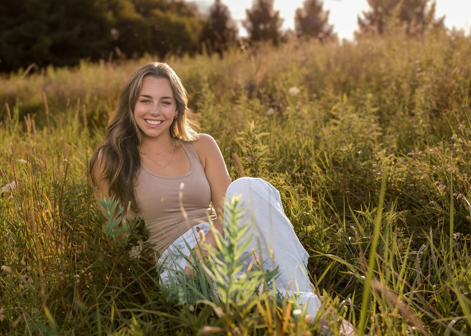 Summer senior portrait session in tall grass during golden hour.