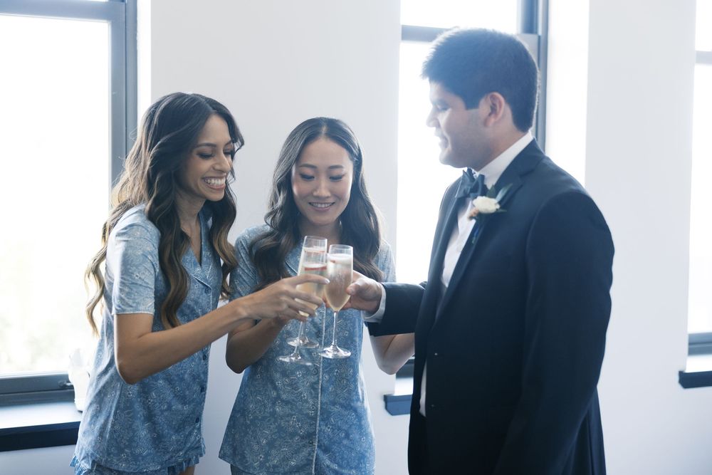 Three well-dressed people toasting with champagne glasses at an elegant indoor gathering.
