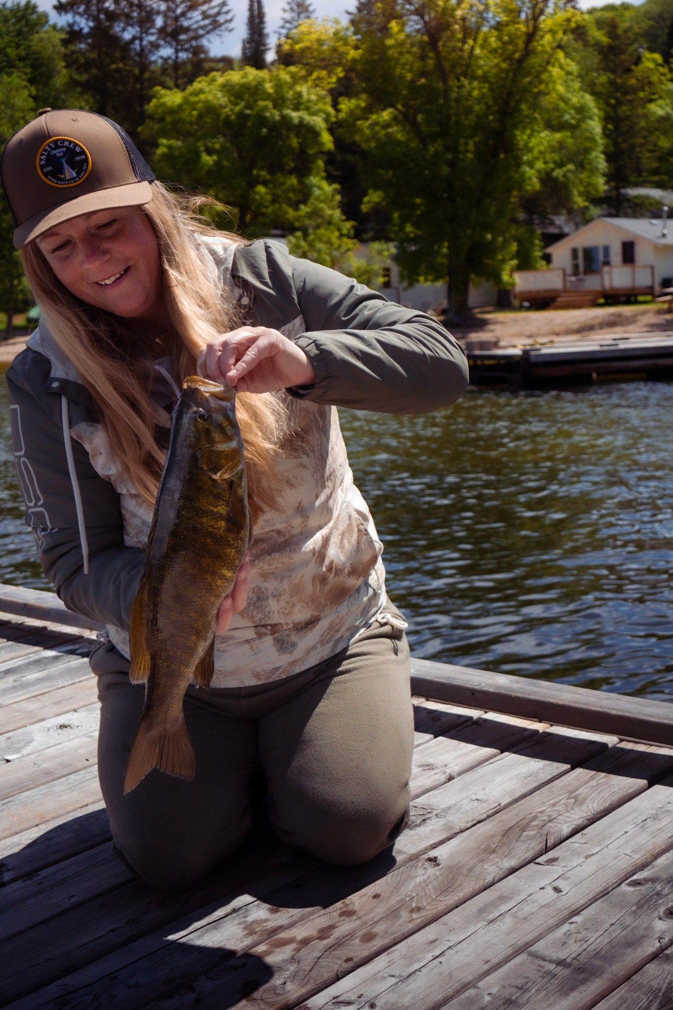 Angler proudly displays their freshly caught smallmouth bass on a lakeside dock.