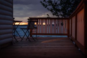 Wooden deck railing silhouetted against a colorful sunset over a calm lake.