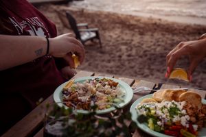 Two plates of fresh salad with crumbled cheese being served outdoors.