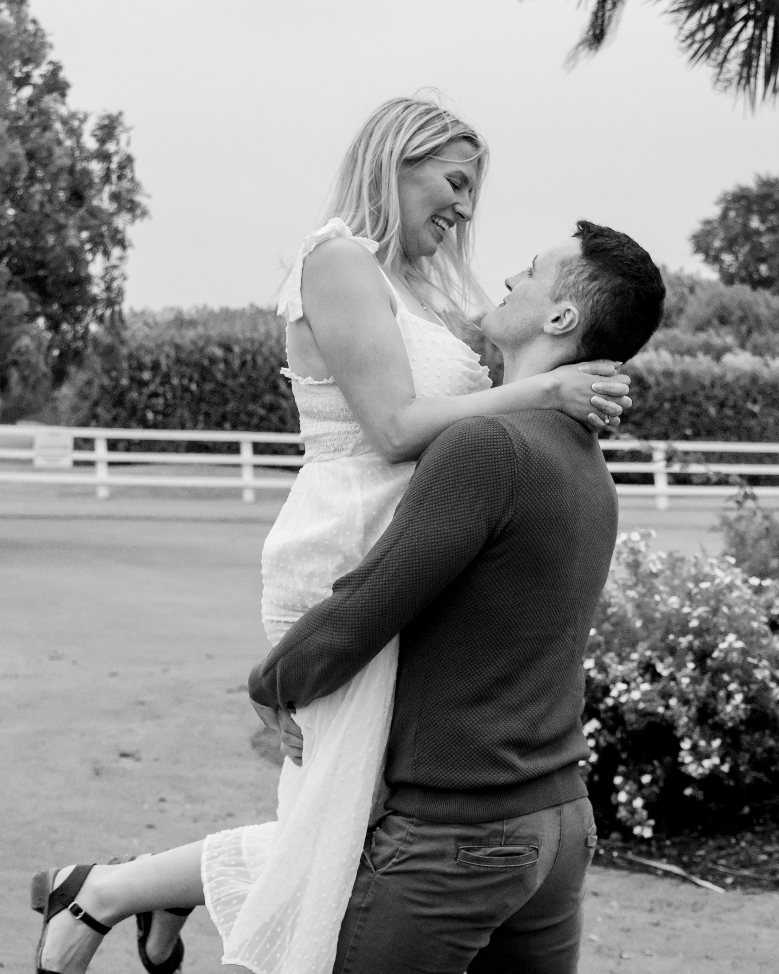 Black and white series of intimate moments between two people near a white fence.