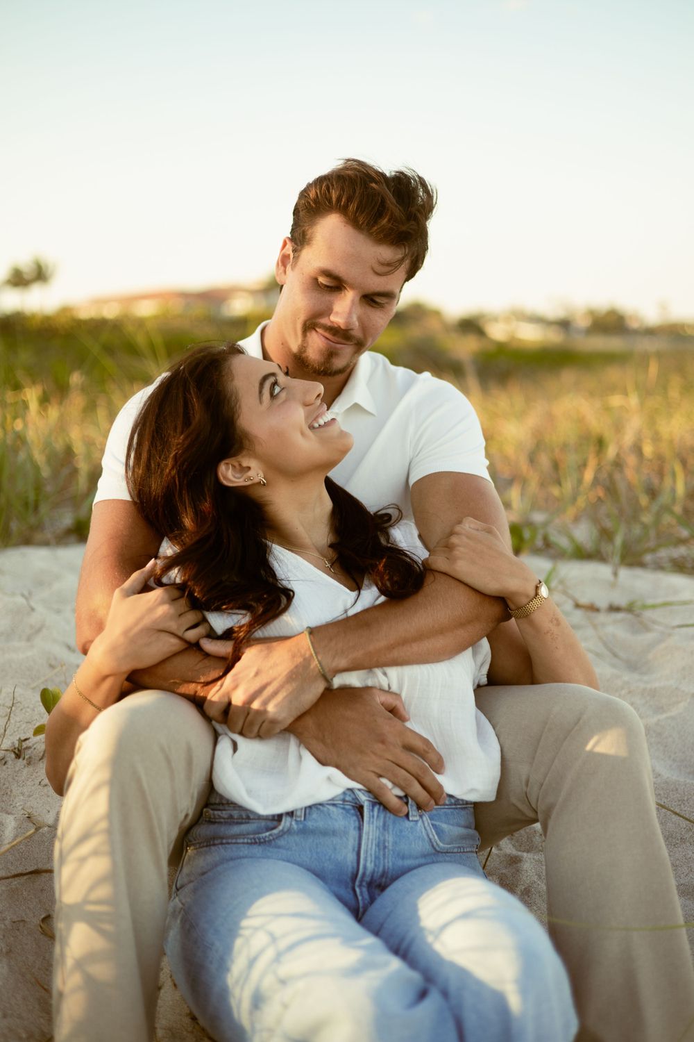 Woman sitting in between a mans legs white looking back into his eyes and he looks down