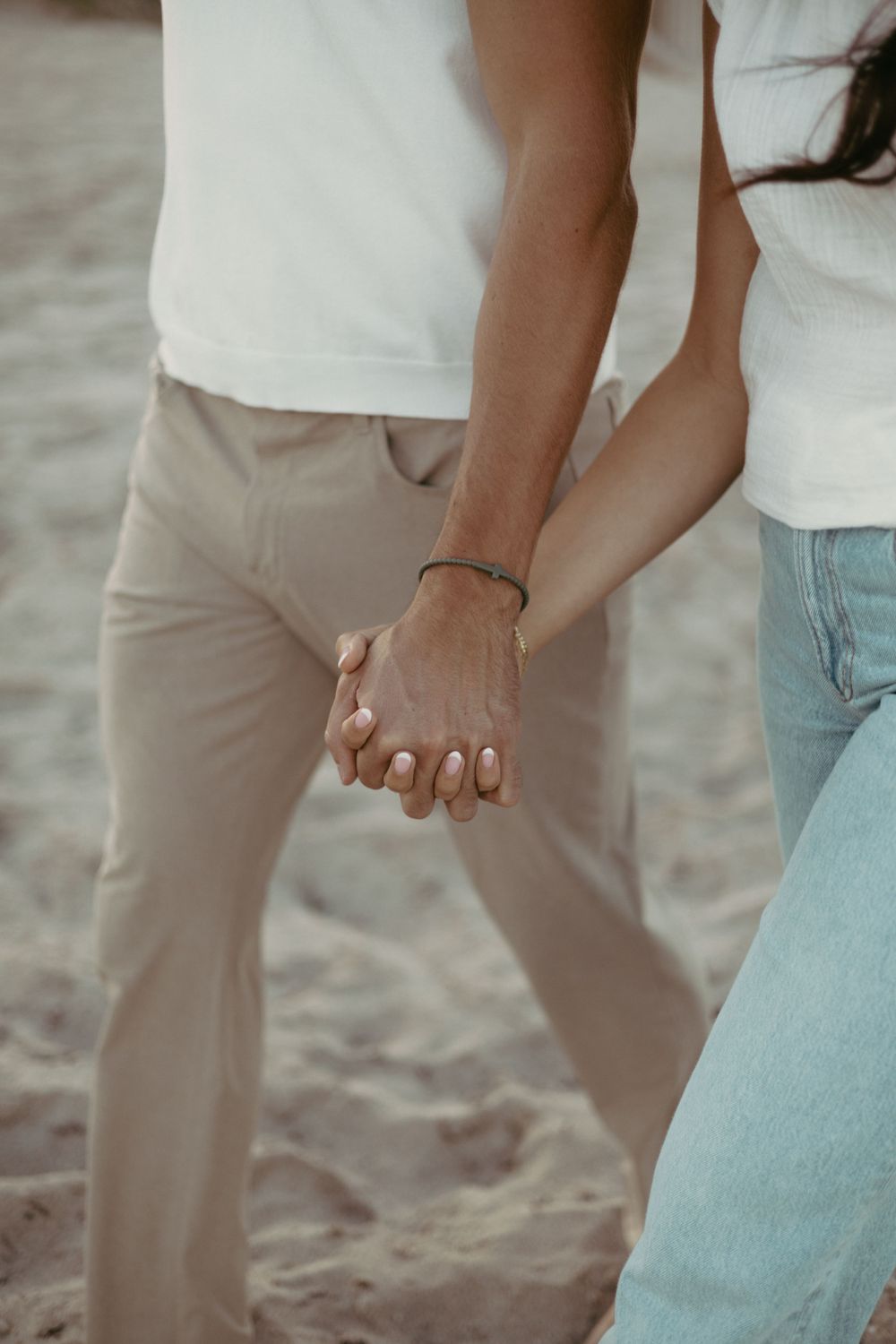 couple holding hands and walking on the sand