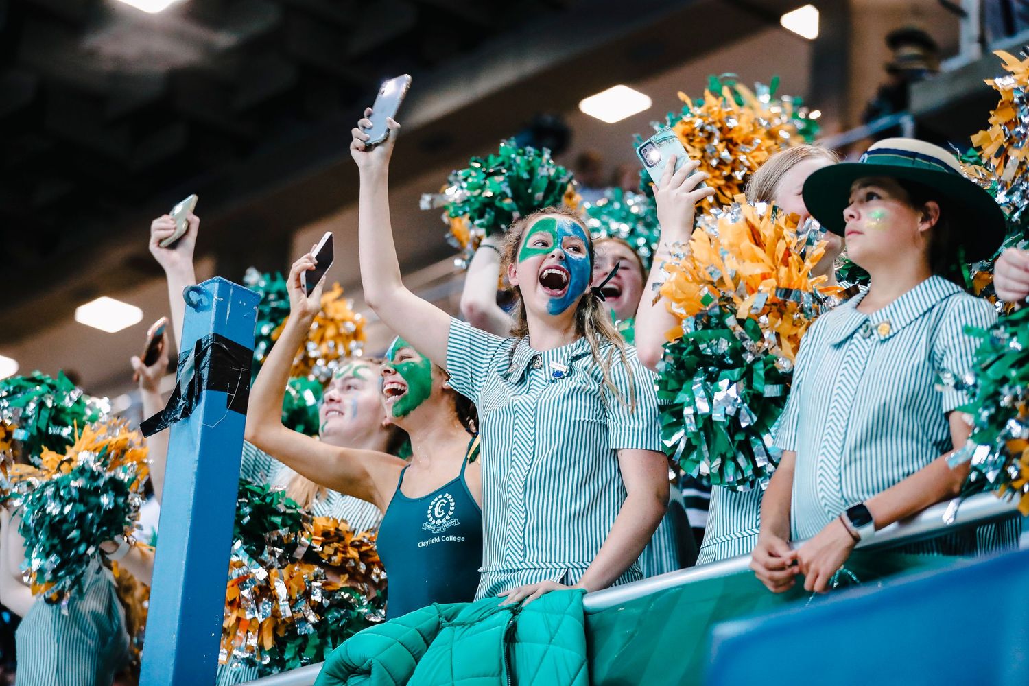 Cheerleaders in striped uniforms cheer with pom poms at sporting event.