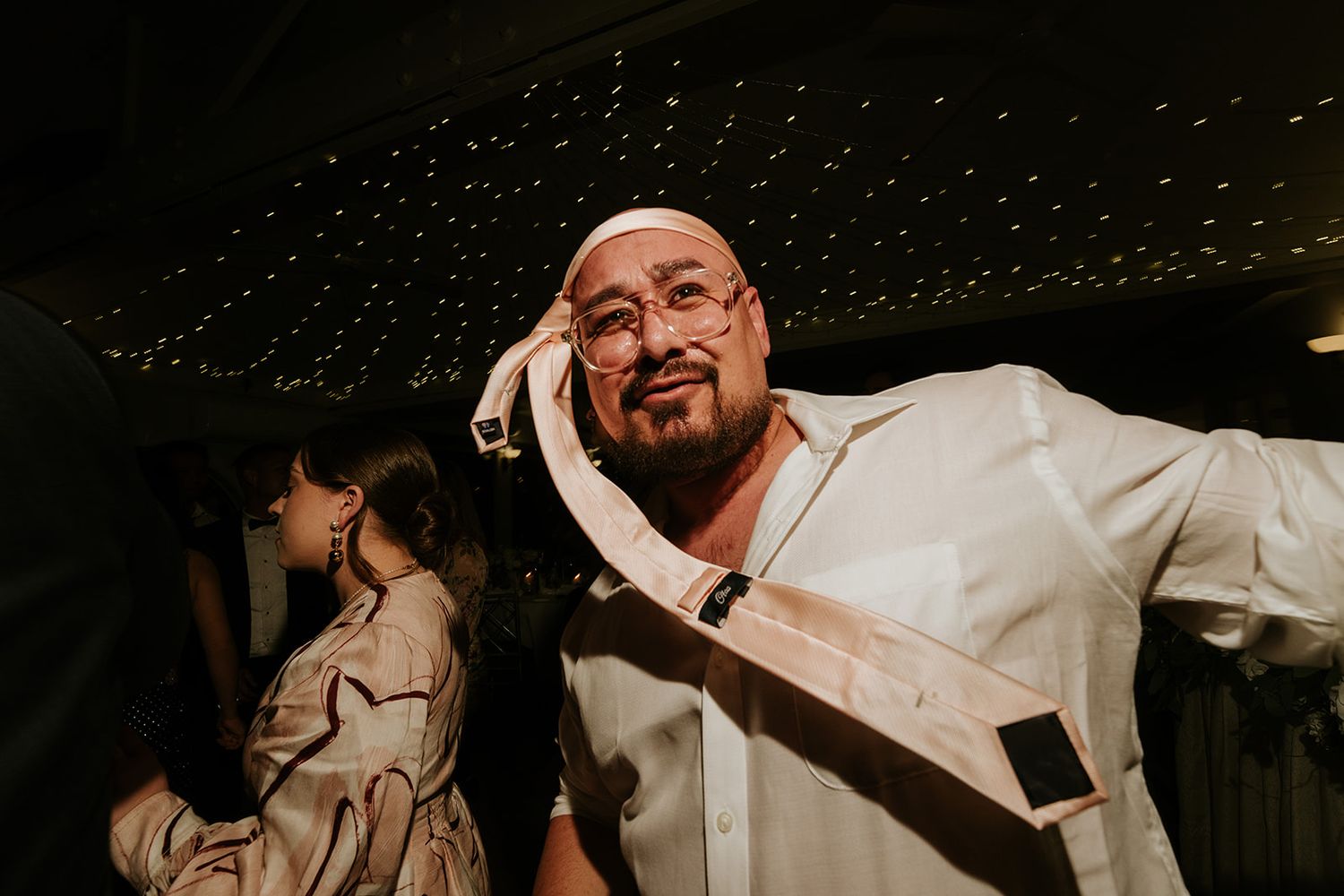 Person in white shirt laughing enthusiastically at a party under starlit ceiling.