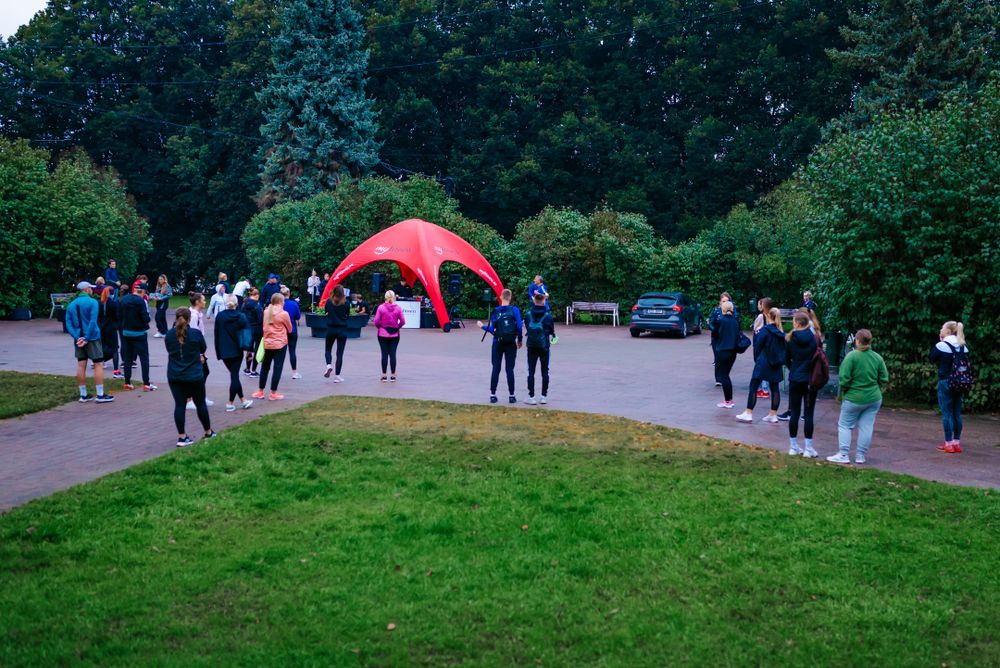 People gathering near a red inflatable arch in a park setting.