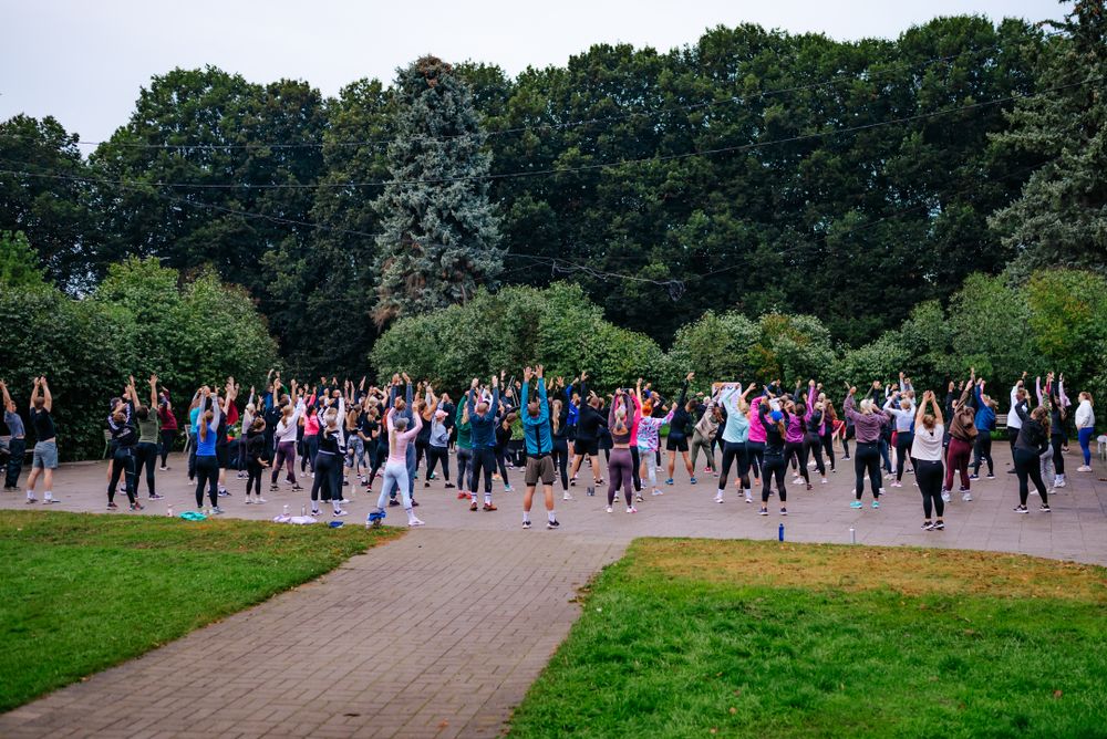 Large crowd of participants spread across a park path during an outdoor fitness event.