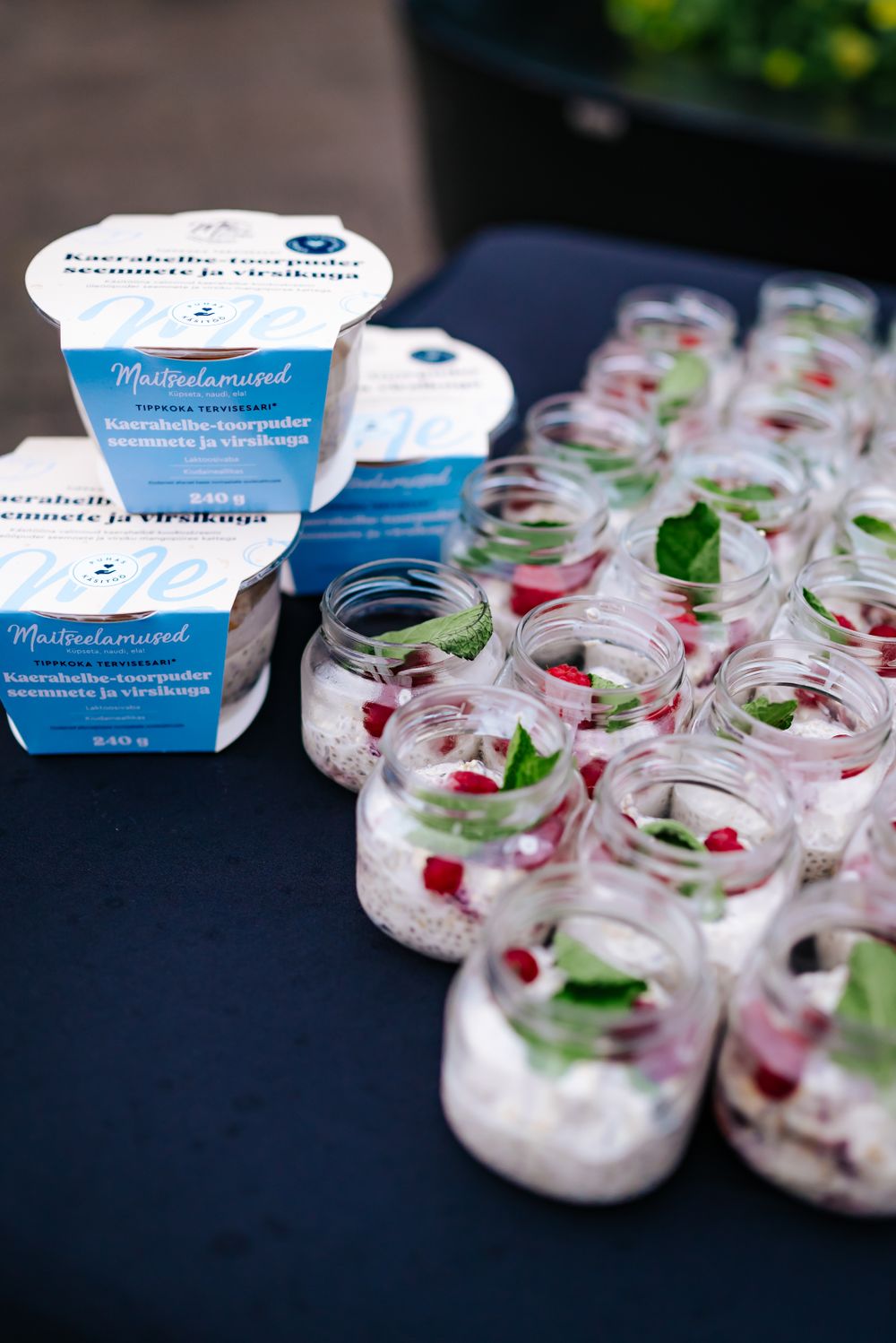 Small glass jars filled with dessert and garnished with berries lined up on a black table.