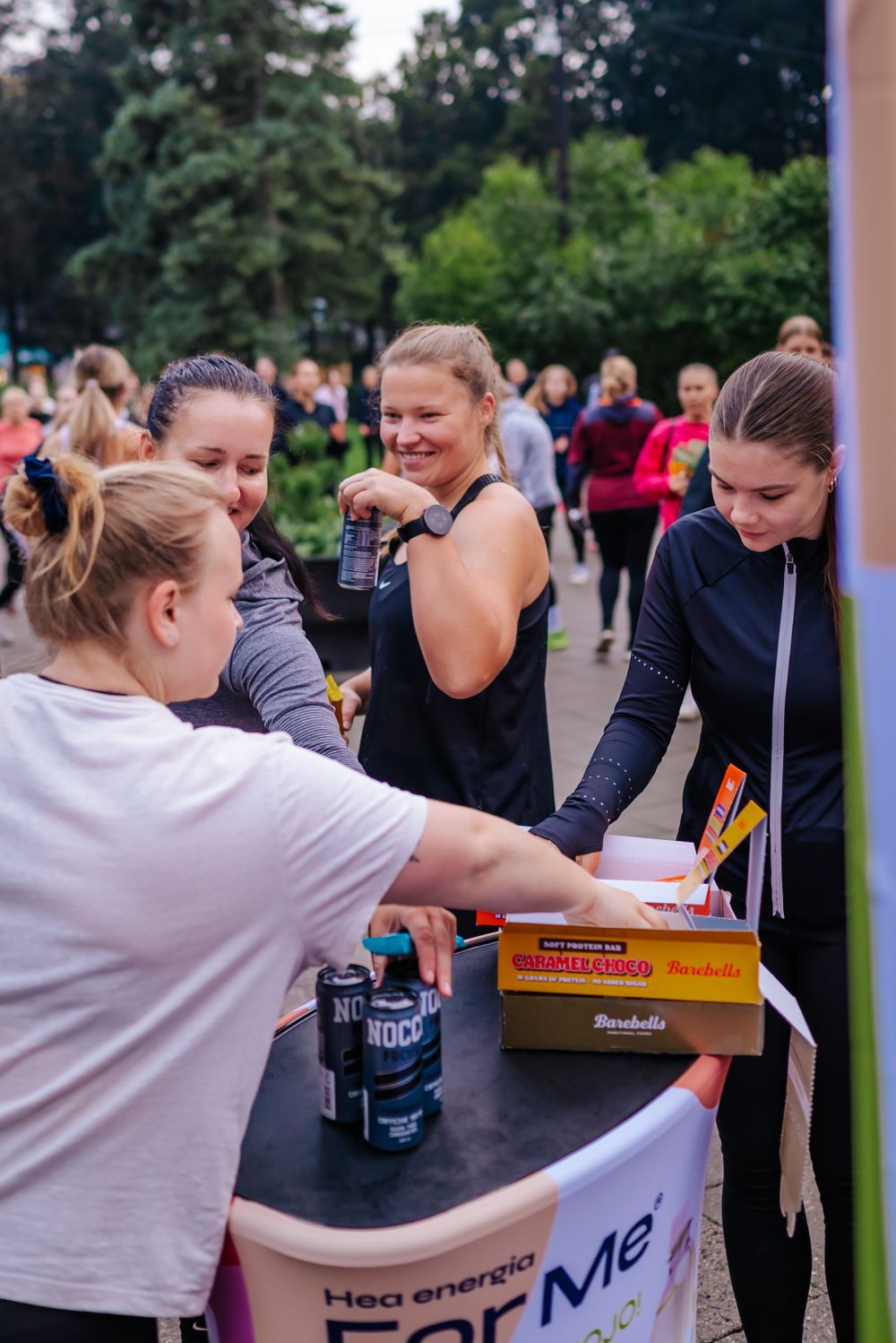 People gathering around a refreshment table at an outdoor fitness event.